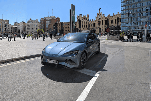 Blue BYD electric vehicle parked in urban city square with historic buildings.